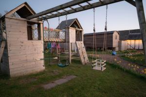 a playground in a garden with a swing at The Shippon Barn - A delightful haven for families in Wirral