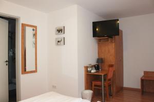 a bedroom with a bed and a table with a tv on the wall at Hotel Waitzingers in Landsberg am Lech
