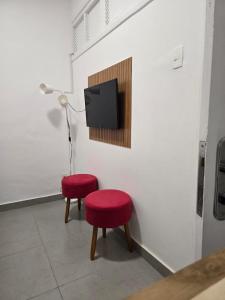 a room with two red stools and a tv on a wall at 100m da praia de Copacabana in Rio de Janeiro
