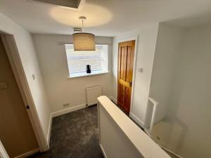 an empty hallway with a window and a stair case at Sea Breeze Cottage short walk to the beach, Nairn in Nairn +11 photos