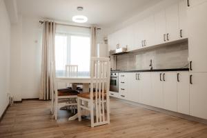 a kitchen with white cabinets and a table and chairs at Als apartament in Târgu Neamț