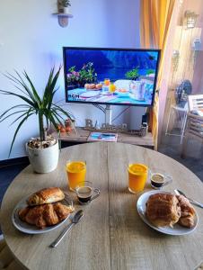 einen Tisch mit zwei Croissants und einem TV in der Unterkunft Apartment with pool in secure residence in Nizza