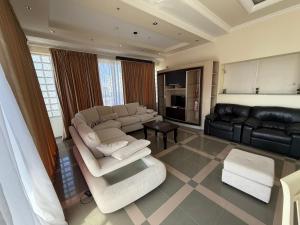 a living room with white furniture and a black couch at Green Garden Villa in Durrës