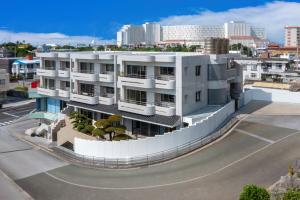 un grand bâtiment blanc avec une ville en arrière-plan dans l'établissement Walking distance to the beach & full of gourmet spots! Up to 8 people, free parking for 2 cars コーディアルステイA2, à Onna