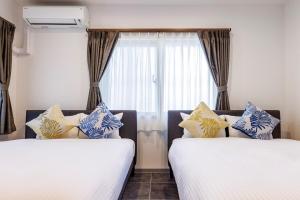 deux lits assis à côté d'une fenêtre dans une pièce dans l'établissement Walking distance to the beach & full of gourmet spots! Up to 8 people, free parking for 2 cars コーディアルステイA2, à Onna