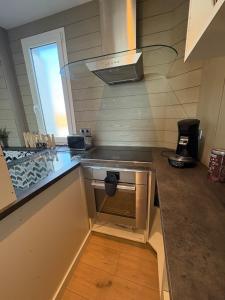 una cocina con fregadero y estufa horno superior en Jade's House, en Donville-les-Bains