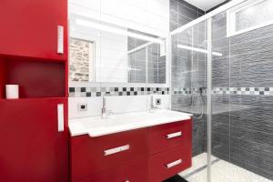 baño rojo con lavabo y ducha en Jade's House, en Donville-les-Bains