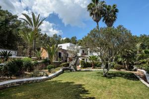 einen Garten mit Palmen und ein Haus in der Unterkunft Can Blay in Santa Eulària des Riu