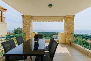 a dining room with a table and chairs on a balcony at Villa Momento by RentalsPro - Poseidi Halkidiki in Kalandra