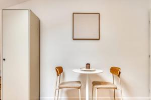 a table and chairs in a room with a white wall at La Suite Sable - Cosy studio - Proche Métro B in Oullins