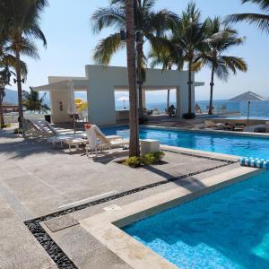 a swimming pool with palm trees and a villa at Beachfront Harbor 171 Condo Ocean View Pool, Gym WiFi in Puerto Vallarta