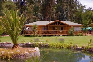 una cabaña de madera con un estanque frente a ella en Olmue Natura Lodge & Spa, en Olmué