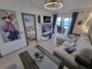 a living room with a couch and a painting of a woman at Cabo Cervera primera linea apartamento de lujo in Torrevieja
