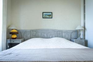 a bedroom with a white bed with two tables and two lamps at Maison Studios & Appartements Les 4 Vents in Luc-sur-Mer