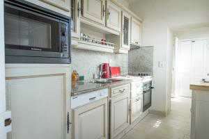 a kitchen with white cabinets and a microwave at Maison Studios & Appartements Les 4 Vents in Luc-sur-Mer