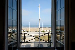an open window with a view of the beach at Maison Studios & Appartements Les 4 Vents in Luc-sur-Mer