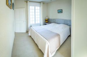 a bedroom with a white bed and a window at Maison Studios & Appartements Les 4 Vents in Luc-sur-Mer