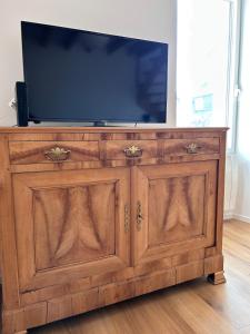 a wooden entertainment center with a flat screen tv on top at La Pause Binicaise - Maison proche plage in Binic-Etables-sur-Mer