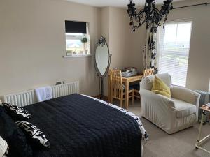 a bedroom with a bed and a chair and a mirror at Atlantic Bliss in Portstewart