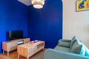 a blue living room with a couch and a tv at Le Petit Nid d'Auray - En plein centre-ville in Auray