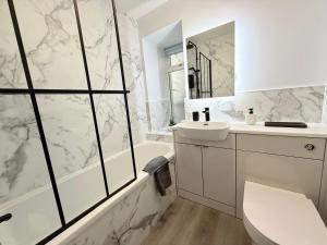 a white bathroom with a tub and a sink at Sea Breeze Cottage short walk to the beach, Nairn in Nairn