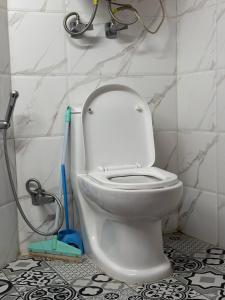 a bathroom with a white toilet with a mop at Nani House the mall road shimla in Shimla +3 photos