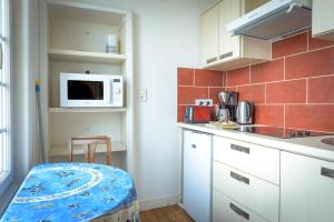a kitchen with a microwave and a chair in it at Maison Studios & Appartements Les 4 Vents in Luc-sur-Mer