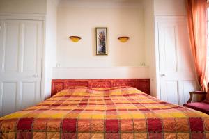 a bedroom with a bed with a checkered blanket at Maison Studios & Appartements Les 4 Vents in Luc-sur-Mer