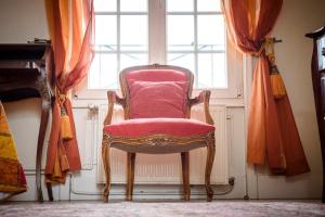 a pink chair sitting in front of a window at Maison Studios & Appartements Les 4 Vents in Luc-sur-Mer