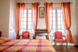 a bedroom with a bed and two chairs at Maison Studios & Appartements Les 4 Vents in Luc-sur-Mer