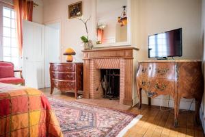 a living room with a fireplace and a television at Maison Studios & Appartements Les 4 Vents in Luc-sur-Mer