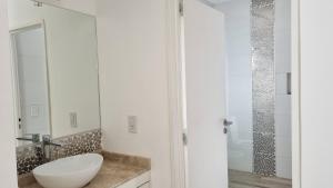 a white bathroom with a sink and a shower at Hermoso duplex a 500m del Paseo de la Costa in Neuquén