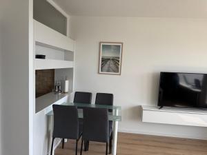 ein Esszimmer mit Tisch und Stühlen und einem Fernseher in der Unterkunft Ostsee Apartment mit Meerblick in Sierksdorf + 7 Fotos