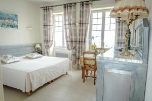 a bedroom with a bed and a table and window at Maison Studios & Appartements Les 4 Vents in Luc-sur-Mer