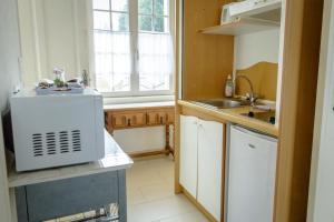a small kitchen with a sink and a window at Maison Studios & Appartements Les 4 Vents in Luc-sur-Mer