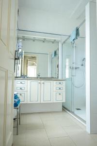 a white bathroom with a shower and a sink at Maison Studios & Appartements Les 4 Vents in Luc-sur-Mer