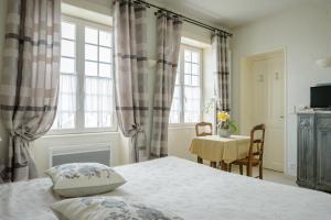 a bedroom with a bed and a table and windows at Maison Studios & Appartements Les 4 Vents in Luc-sur-Mer