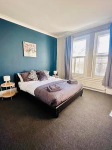 Un dormitorio con una cama grande con paredes azules. en Richmond charm cozy apartment, en Richmond upon Thames