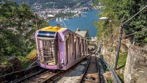 a purple train on the tracks next to a lake at B&B Villa Mirandola in Brunate