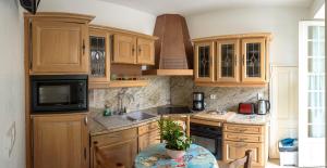 a kitchen with wooden cabinets and a table with a plant at Maison Studios & Appartements Les 4 Vents in Luc-sur-Mer