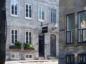 ein Steingebäude mit einer blauen Tür und Fenstern in der Unterkunft Hôtel Maison du Fort in Québec