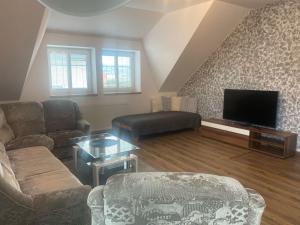 a living room with a couch and a tv at Penzion U Jandů in Běhařov