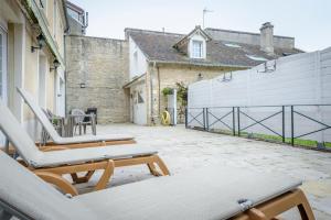 a patio with two lounge chairs and a fence at Maison Studios & Appartements Les 4 Vents in Luc-sur-Mer