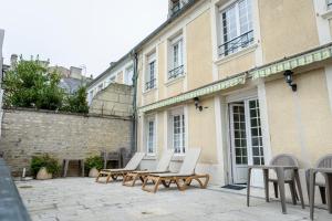 a group of chairs and tables on a patio in front of a building at Maison Studios & Appartements Les 4 Vents in Luc-sur-Mer