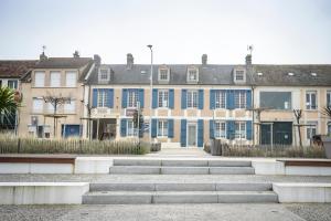 a large building with blue windows and stairs in front at Maison Studios & Appartements Les 4 Vents in Luc-sur-Mer
