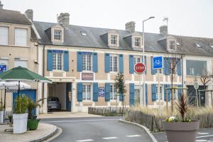 a building with blue windows and a stop sign at Maison Studios & Appartements Les 4 Vents in Luc-sur-Mer