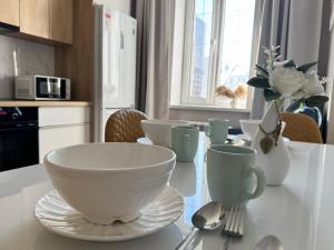 eine Küche mit einem Tisch mit Schüsseln und Tassen darauf in der Unterkunft Новая квартира рядом с ЭКСПО АЭРОПОРТОМ ПРЕЗИДЕНТСКАЯ БОЛЬНИЦА Венский 29б in Astana