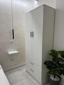 a white cabinet in a bathroom with a potted plant at Soffio di mare Apartment in Stazione di Montenero-Petacciato +9 photos