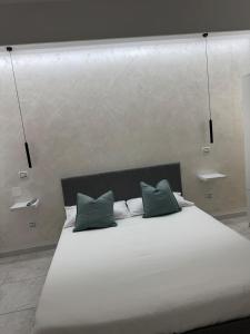 a large white bed with two green pillows on it at Soffio di mare Apartment in Stazione di Montenero-Petacciato
