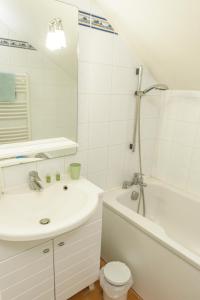 a bathroom with a sink and a tub and a toilet at Maison Studios & Appartements Les 4 Vents in Luc-sur-Mer